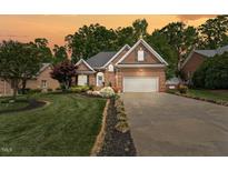 Beautiful brick home with a well-manicured lawn and two-car garage under a dramatic sunset sky at 480 Whitt Ave, Burlington, NC 27215