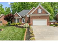 Charming brick home featuring a manicured lawn, attached two car garage, and lush landscaping at 480 Whitt Ave, Burlington, NC 27215