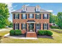Charming brick two-story home with black shutters, dormers, well-manicured landscaping, and inviting entrance at 1009 Sarazen Dr, Clayton, NC 27527