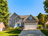 Charming two-story home featuring a well-manicured lawn, blue front door, and attached two-car garage at 1106 Purple Glory Dr, Apex, NC 27502