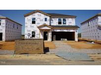 New construction home with Tyvek wrap, showing the initial stages of the building process and attached garage at 1112 Landen Creek Ln, Zebulon, NC 27597