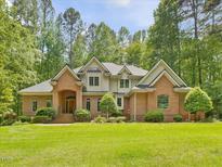 Stunning brick home featuring arched entry, manicured lawn, and mature trees at 1428 Gray Bluff Trl, Chapel Hill, NC 27517