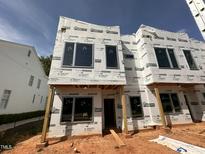 Exterior view of a new construction home with large windows and protective wrap at 1521 Sunrise Ave, Raleigh, NC 27608