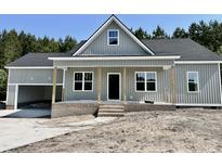 Charming single-story home boasts a welcoming porch, gray siding and an attached garage with natural light and a yard to be landscaped at 2802 Packing Plant Rd, Smithfield, NC 27577