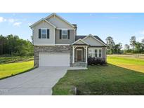 Charming two-story home featuring stone accents, a welcoming front porch, attached garage, and a well-manicured lawn at 482 Olivia Crossing Ct, Four Oaks, NC 27524