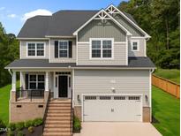 Two-story home with grey siding, black shutters, a brick stair entrance and attached two-car garage at 5 Cinnamon Teal Way, Youngsville, NC 27596