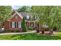 Charming two-story brick home with manicured lawn and lush landscaping, including mature trees at 708 Mill Pointe Way, Elon, NC 27244