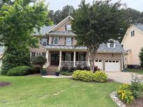 Charming brick home featuring a manicured lawn, covered front porch, and a two-car attached garage at 1021 Golden Star Way, Wake Forest, NC 27587
