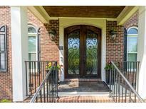 Inviting brick home entrance featuring an ornate, dark wood front door and decorative ironwork at 5025 Martin Farm Rd, Raleigh, NC 27613
