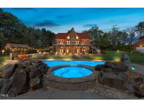 Beautiful log home featuring a swimming pool, jacuzzi, and an outdoor tiki bar surrounded by lush greenery at 6707 Frieden Church Rd, Gibsonville, NC 27249