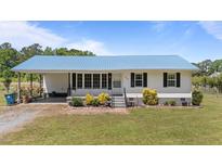 Charming single-story home featuring a metal roof, covered porch, and well-manicured lawn at 8163 Julian Rd, Dunn, NC 28334
