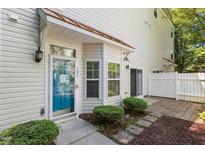 Inviting townhome entrance featuring a bright blue door, manicured landscaping, and a charming covered porch at 11710 Mezzanine Dr # 101, Raleigh, NC 27614