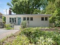 Charming single-story home features a tidy front yard, classic exterior, and a pop of color from its turquoise-painted front door at 1521 N Duke St, Durham, NC 27701