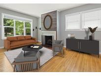 Cozy living room featuring a fireplace, light hardwood floors, a gray rug, and large windows with natural light at 1521 N Duke St, Durham, NC 27701