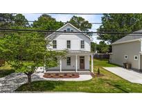 Charming two-story white home featuring a covered porch with elegant columns and landscaped front yard at 412 W Stallings St, Clayton, NC 27520