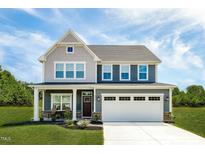 Two-story home with a two-car garage, covered porch and manicured lawn under a bright blue sky at 569 Freedom Trail Dr, Willow Springs, NC 27592