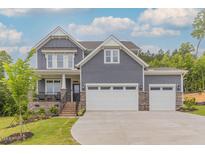 Beautiful two-story home featuring gray siding, stone accents, and a spacious three-car garage at 1112 Prominence Dr, Durham, NC 27712