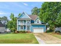 Charming two-story blue home featuring a double front porch, attached garage, and well-manicured lawn at 112 Nelson Ln, Clayton, NC 27527