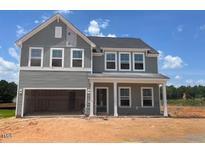 Charming two-story home featuring a welcoming porch and large open garage under a clear blue sky at 128 Sagamore Avenue, Angier, NC 27501