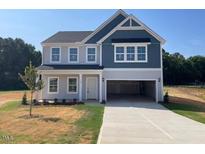 Two story home with a blue and grey exterior, open garage, and large concrete driveway at 129 Sagamore Avenue, Angier, NC 27501