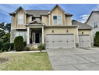 Charming two-story home features a three car garage, stone accents, and a manicured lawn at 1549 Lily Creek Dr, Cary, NC 27518