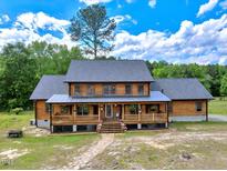 Charming two-story log home with a welcoming covered front porch and beautiful landscaping at 2092 Winwood Farm Rd, Creedmoor, NC 27522