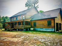Rustic log home with a covered porch, blending charm and country appeal in a serene setting at 2092 Winwood Farm Rd, Creedmoor, NC 27522
