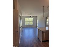 Bright living room featuring a ceiling fan, large window, and hardwood flooring at 2418 Gathering Square Ct, Fuquay Varina, NC 27526