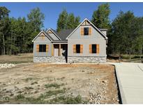 Charming two-story home with wood shutters, stone accents, gray siding, and a driveway ready for landscaping at 260 Pilot Ridge Rd, Zebulon, NC 27597
