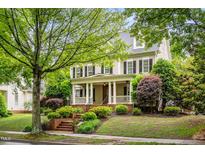 Inviting two-story home featuring a charming front porch and professionally landscaped yard at 3821 Falls River Ave, Raleigh, NC 27614