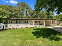 Charming home featuring a well-maintained lawn, brick facade, covered entryway, and a convenient carport at 5208 Melbourne Rd, Raleigh, NC 27606