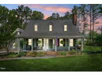 Charming home featuring a welcoming front porch, dormer windows, and manicured lawn and beautiful landscaping at 100 Mill Creek Dr, Fuquay Varina, NC 27526