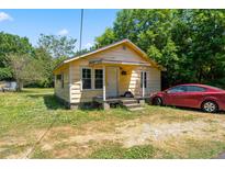 Exterior view of a small yellow single-story home with a front porch and a red car parked to the side at 105 E Cole St, Dunn, NC 28334