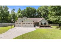 Charming single-story home with a well-manicured lawn, three-car garage, and extended driveway with basketball hoop at 123 Terawood Farm Dr, Willow Springs, NC 27592