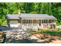 Charming single-story home with a welcoming front porch and attached garage, surrounded by lush greenery at 2100 Fort Dr, Clayton, NC 27520