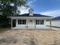 Charming, newly built single-story home featuring a classic covered porch and a white exterior finish at 211 E Washington St, Coats, NC 27521