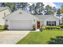Charming one-story home features a red front door, an attached garage, and manicured lawn at 217 Braxcarr St, Holly Springs, NC 27540