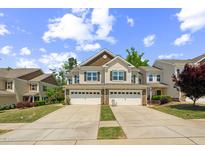 Beautiful townhome featuring an attached two-car garage and manicured lawn, offering modern convenience at 221 Mayfield Dr, Apex, NC 27539