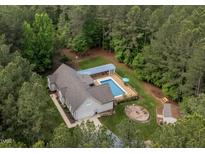 Beautiful aerial view of the home, showcasing the pool, firepit and surrounding wooded acreage at 3653 Range Rd, Stem, NC 27581