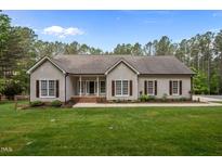 Charming single-story home featuring a manicured lawn, symmetrical windows, and professional landscaping at 3653 Range Rd, Stem, NC 27581