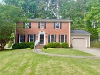 Charming two-story red brick home with a well-manicured lawn and mature trees at 5021 Lansdowne Dr, Durham, NC 27712