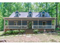 Charming home featuring a welcoming front porch, dormer windows, and lush landscaping surrounded by mature trees at 603 Gentry Ln, Hillsborough, NC 27278