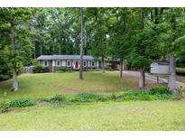 Inviting single-story home with a red door, manicured lawn, and mature trees providing ample shade at 606 Chalice St, Durham, NC 27705