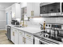 Modern kitchen featuring white cabinets, gold hardware, stainless steel appliances, and white subway tile backsplash at 1022 Early Rise St St, Raleigh, NC 27610