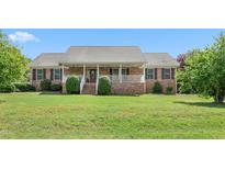 Charming single-story brick home with a welcoming front porch and lush green lawn at 1199 Cesar Ct, Graham, NC 27253
