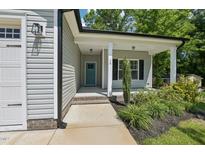 Charming home featuring a covered entrance, well-manicured landscaping, and a welcoming blue door at 15 Nottingham Pl, Smithfield, NC 27577