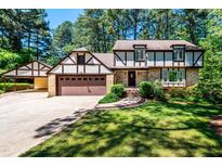 Charming two-story home with brick and Tudor-style accents, an attached garage, and well-manicured landscaping at 1604 Westbridge Ct, Raleigh, NC 27606
