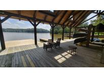 View of the wood dock and lake with seating and canoe storage at 179 Forest Bridge Rd, Youngsville, NC 27596