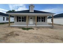 Charming home with a covered porch and well-maintained landscaping at 221 E Washington St, Coats, NC 27521