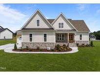 Inviting home featuring a stone foundation, manicured lawn, beautiful landscaping, and a charming front porch at 25 Deer Tail Ln # 52, Fuquay Varina, NC 27526
